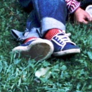 Two children sitting on grass with toy truck.