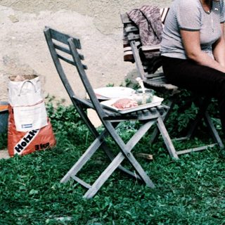 Woman sitting outdoors with child playing ball.