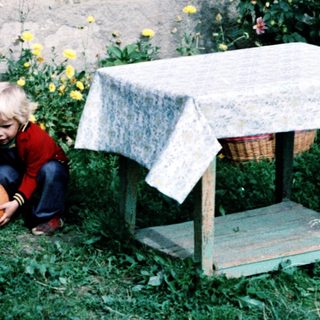 Woman sitting outdoors with child playing ball.