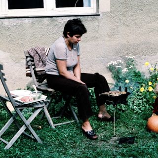 Woman sitting outdoors with child playing ball.