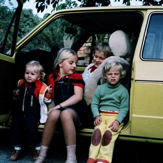 Four children sitting in open van door.