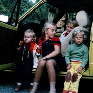Four children sitting in open van door.