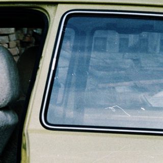 Three children sitting in open car doors.