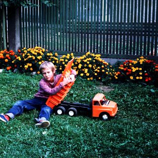 Boy playing with toy truck in grassy area.