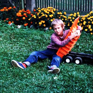 Boy playing with toy truck in grassy area.