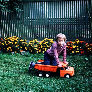 Two children playing with toy truck outdoors.