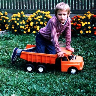 Two children playing with toy truck outdoors.
