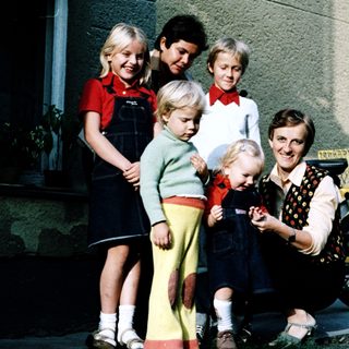 Family posing together outdoors near a house.