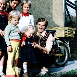 Family posing together outdoors near a house.