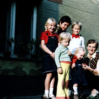 Family posing together outdoors near a house.