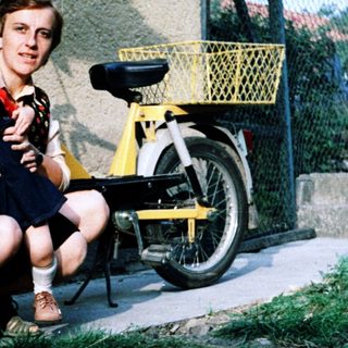 Family posing together outdoors near a bicycle.