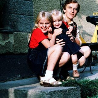 Family posing together outdoors near a bicycle.