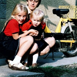 Family sitting on steps outside with bicycle.