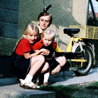 Family sitting on steps outside with bicycle.