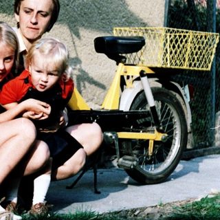 Family sitting on steps outside with bicycle.