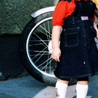 Young girl standing beside yellow moped.