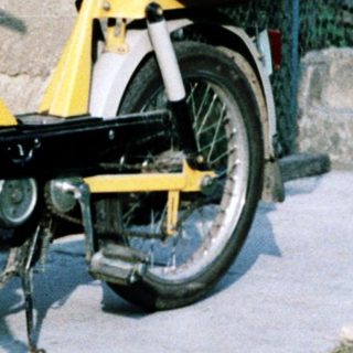Young girl standing beside yellow moped.