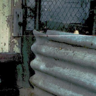 Abandoned, rusted metal structure with broken door.