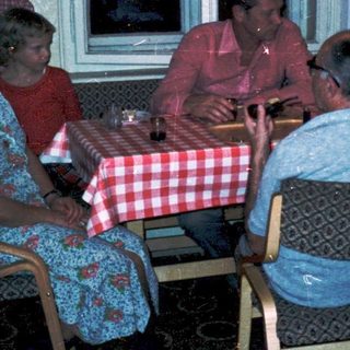 Family gathering around a table in a cozy indoor setting.