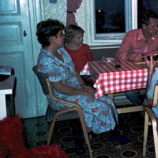 Family gathering around a table in a cozy indoor setting.