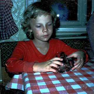 Child eating alone at table with checkered cloth.