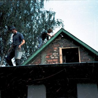 Two men installing roofing on a house.
