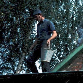 Two men installing roofing on a house.