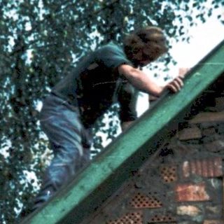 Two men installing roofing on a house.