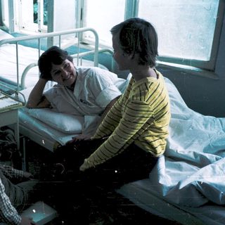 Hospital room with patient, nurse, and visitors.