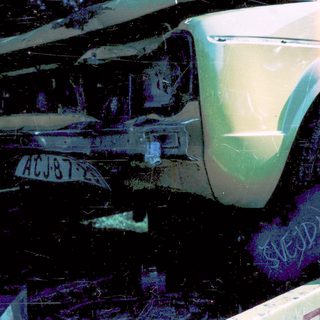 Severely damaged light green vehicle on tow truck.