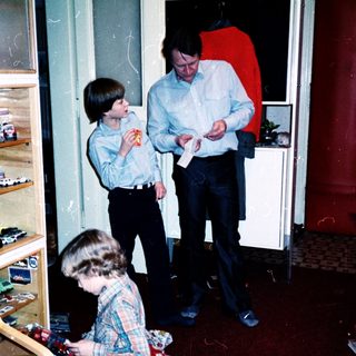 Three people in a kitchen playing with toys.