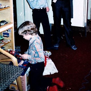 Three people in a kitchen playing with toys.