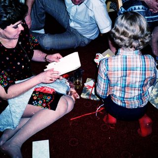 People opening wrapped gifts in a cozy indoor setting.