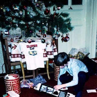 Person assembling electronic device surrounded by Christmas gifts.