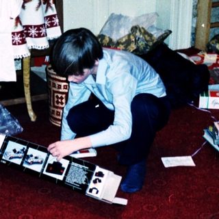 Person assembling electronic device surrounded by Christmas gifts.