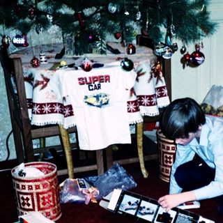 Person assembling electronic device surrounded by Christmas gifts.