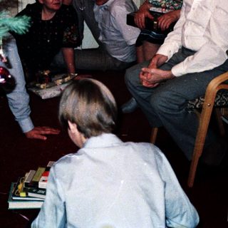 Family gathering around decorated Christmas tree indoors.