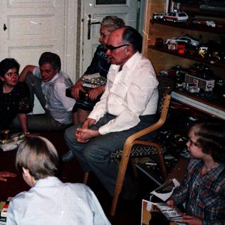 Family gathering around decorated Christmas tree indoors.