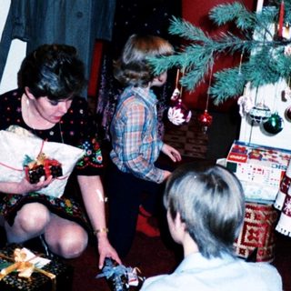 Family gathering opening holiday gifts indoors.
