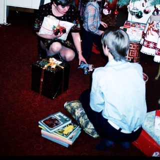 Family gathering opening holiday gifts indoors.