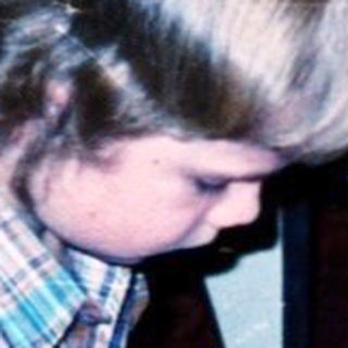 Child assembling toy camera on floor with gift boxes.