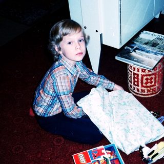 Child playing with Lego on carpet near open laundry.