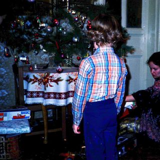 Two people decorating a Christmas tree indoors.