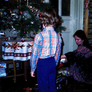 Two people decorating a Christmas tree indoors.