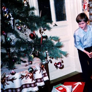 Family opening Christmas presents by tree.