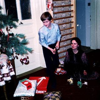 Family opening Christmas presents by tree.