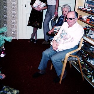 Family gathering with elderly man receiving gift.