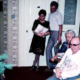 Family gathering with elderly man receiving gift.