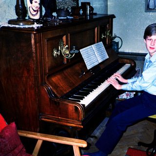 Young boy playing piano indoors with sheet music.