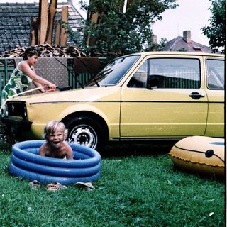 Two children playing in backyard with inflatable pool.